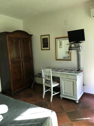 1 dormitorio con escritorio, TV y silla en Agriturismo Serra San Biagio, en Calatabiano