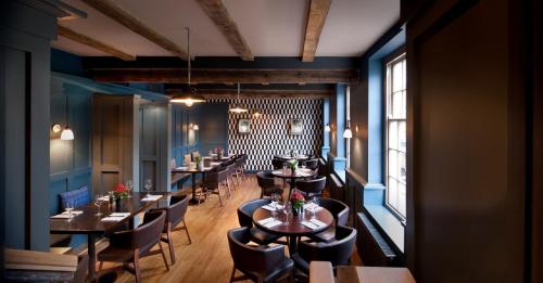 un restaurante con mesas y sillas en una sala con paredes azules en The Crown And Thistle, en Abingdon