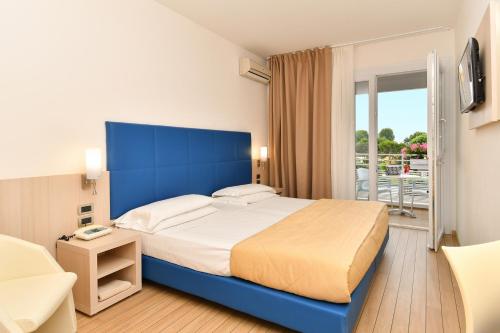 a bedroom with a large bed with a blue headboard at Centro Vacanze Pra' delle Torri in Caorle