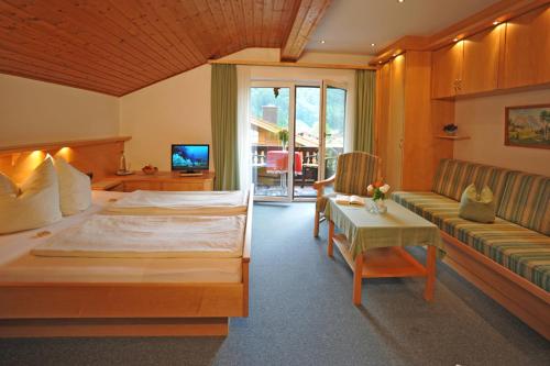 - une chambre avec un grand lit et un canapé dans l'établissement Gästehaus Bartholomäus, à Oberwössen