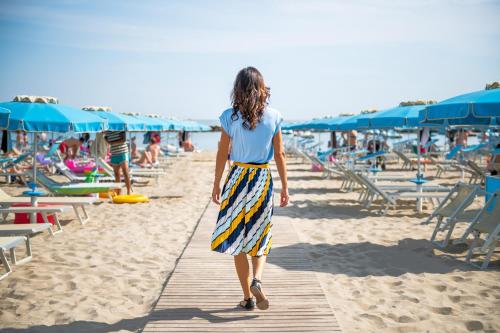a woman walking down a wooden path on the beach at Hotel Panorama in Cattolica