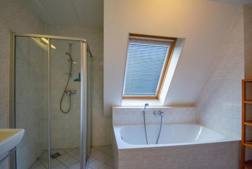 een badkamer met een bad en een douche en een raam bij Duinerei appartement B301 - Groote Keeten in Callantsoog