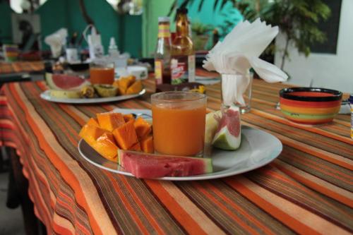 a table with a plate of fruit and a glass of juice at HOMELAND SWAHILI LODGE Nungwi Backpacker Apartments BUDGET in Nungwi