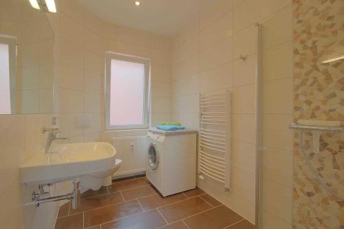 a bathroom with a sink and a washing machine at Gaestehaus Dorum 01 in Dorum