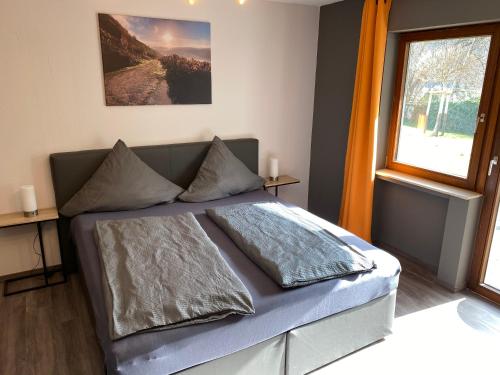 ein Schlafzimmer mit einem Bett mit Kissen und einem Fenster in der Unterkunft Ferienweingut Peter-Jos. Hauth in Bernkastel-Kues