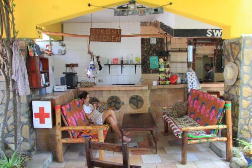 a man sitting on a chair in a kitchen at HOMELAND SWAHILI LODGE Nungwi Backpacker Apartments BUDGET in Nungwi