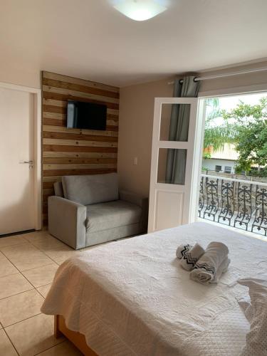 a bedroom with a bed and a couch and a television at Recanto da Sol in Florianópolis