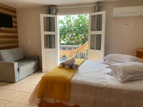 a bedroom with a bed and a chair and a window at Recanto da Sol in Florianópolis