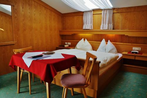 ein Schlafzimmer mit einem Bett und einem Tisch mit einem roten Tischtuch in der Unterkunft Landhaus Gletschermühle in Bad Gastein