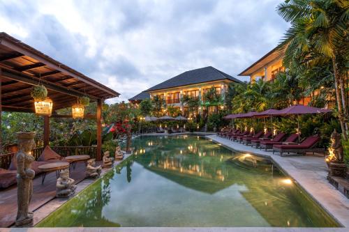 a pool in a resort with chairs and umbrellas at Sahaja Sawah Resort in Tabanan