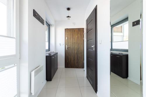 a hallway with a wooden door and a bathroom at Victus Apartamenty, Apartament Villa Sunrise in Sopot