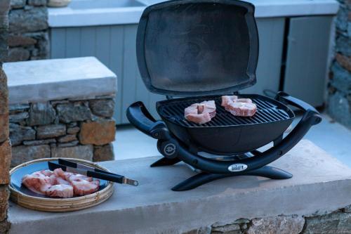 a grill with four pink chickens on it next to a basket at Phos Villas Tinos in Agios Romanos