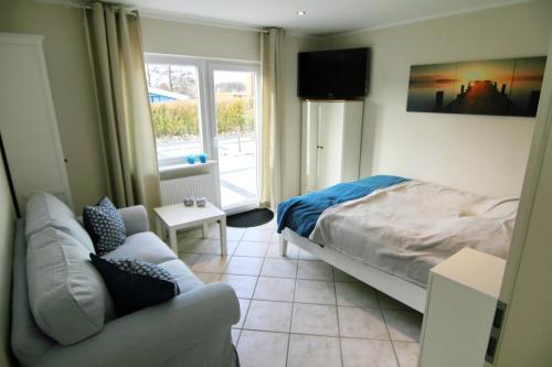 a bedroom with a bed and a couch and a window at Möwennest in Schönhagen