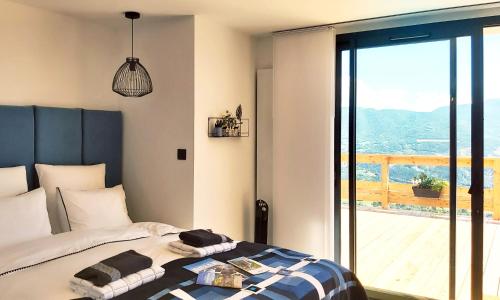 um quarto com uma cama e uma grande janela de vidro em Katsoleil em La Bâtie-Neuve