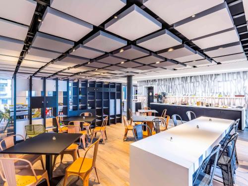 a restaurant with tables and chairs and a bar at ibis Styles Basel City in Basel