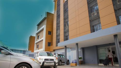 a parking lot with cars parked in front of a building at Hotel La Casa Cielo in Cotonou