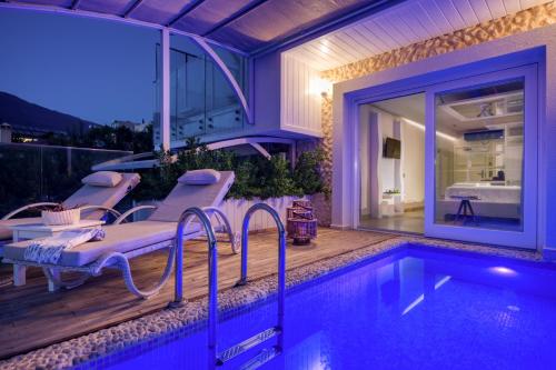 a swimming pool with chairs next to a house at Peninsula Gardens Hotel in Kas