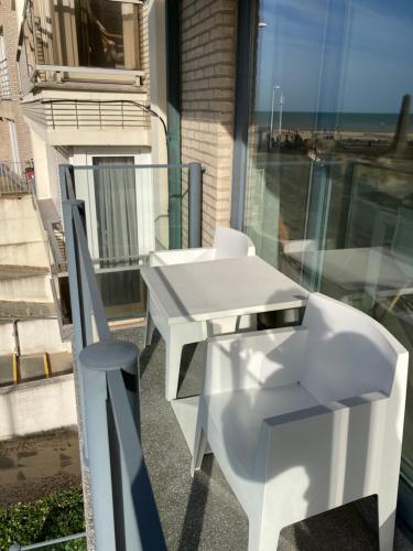 d'une table et d'une chaise blanches sur un balcon. dans l'établissement Blankeduyn Koksijde, à Coxyde