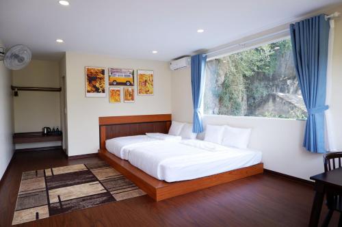 a bedroom with a bed and a window with blue curtains at Ninh Binh The View Point Home & Spa in Ninh Binh