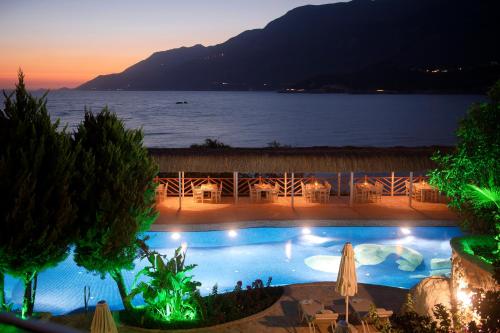 a pool with a view of the ocean at night at Peninsula Gardens Hotel in Kas