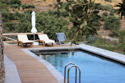 a swimming pool with two chairs and an umbrella at Kea Village Suites & Villas in Ioulida