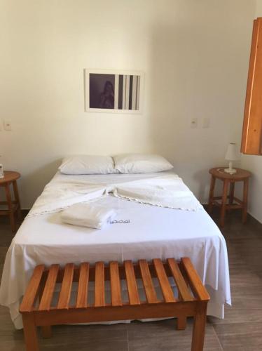 a white bed with a wooden bench next to it at Loft Vila do Sossego in Pirenópolis