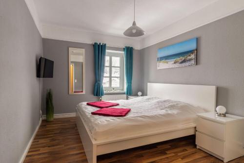 ein Schlafzimmer mit einem Bett mit zwei roten Handtüchern darauf in der Unterkunft Haus Godewind Typ 4 in Binz