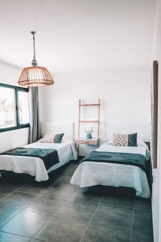 two beds in a white room with a lamp at Casa Tenique in Lajares