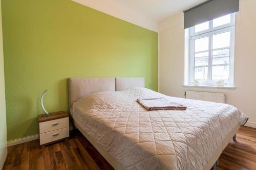 a bedroom with green walls and a bed and a window at Haus-Godewind-Typ-3-1 in Binz