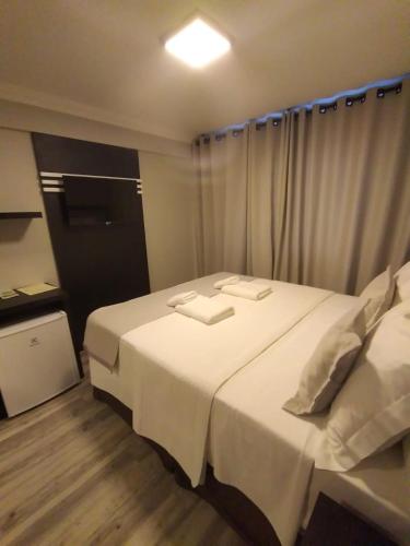 a bedroom with a large bed with white sheets at Navega Beach Palace Hotel in Navegantes