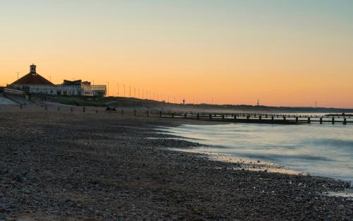a beach at sunset with a pier and a building at Aberdeen Quiet City Apartment, Ferryhill in Aberdeen