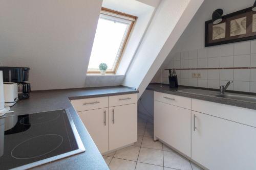 a kitchen with white cabinets and a sink and a window at Haus-Godewind-Typ-4-1 in Binz