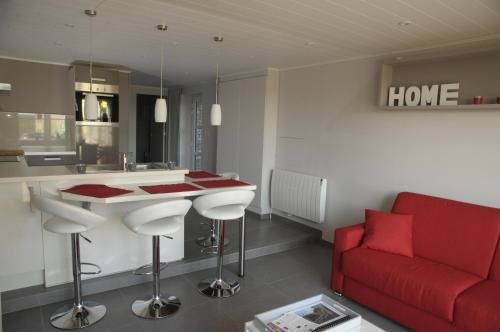 een woonkamer met een rode bank en een keuken bij Le Clos Sigebert in Libramont