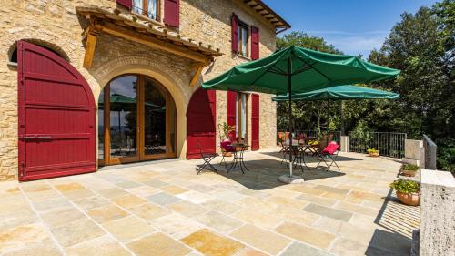 a patio with two tables and a green umbrella at TENUTA DI MACERICCA 10, Emma Villas in Poggibonsi