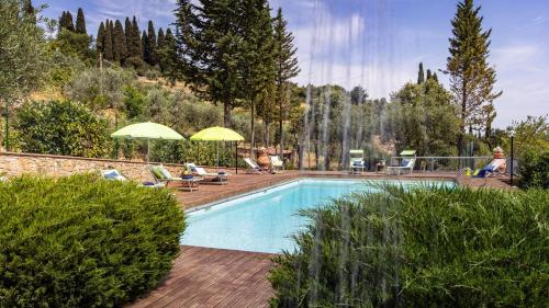a swimming pool with two people sitting under umbrellas in a yard at TENUTA DI MACERICCA 10, Emma Villas in Poggibonsi