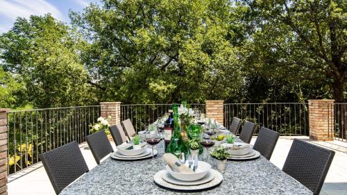 a long table with chairs and a table with plates and flowers at TENUTA DI MACERICCA 10, Emma Villas in Poggibonsi