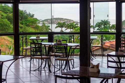 ein Zimmer mit Tischen und Stühlen und einem großen Fenster in der Unterkunft Hotel Ilha Branca Inn in Búzios
