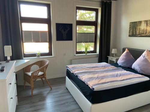 a bedroom with a bed and a desk and two windows at Harzer Ferienlodge in Wernigerode