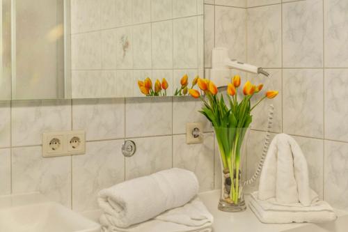 a bathroom with orange tulips in a vase on a sink at Ferienwohnung Brugger 4 Personen in Kaltenbach