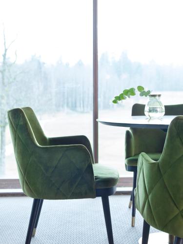 a dining room with two green chairs and a table at Öijared Resort in Floda