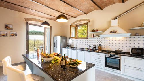 a kitchen with a counter with a bowl of fruit on it at TENUTA DI MACERICCA 10, Emma Villas in Poggibonsi