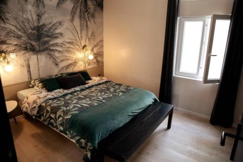 a bedroom with a bed with a tropical wallpaper at T2 au calme , Centre Historique , Entrée Autonome in Montélimar
