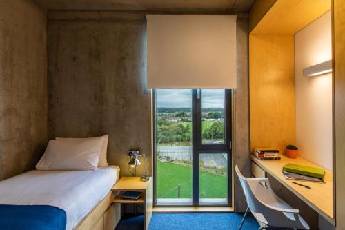 um quarto com uma cama, uma secretária e uma janela em Maynooth Campus Apartments em Maynooth