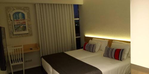 a hotel room with a bed with two pillows at Hospedaria Frangaria in Faro