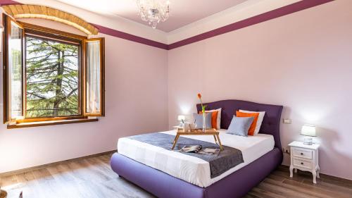 a bedroom with a purple bed and a window at TENUTA DI MACERICCA 10, Emma Villas in Poggibonsi