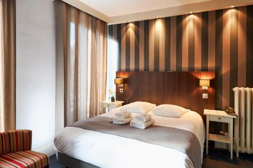 a hotel room with a bed with two teddy bears on it at Hotel Les Negociants in Valence