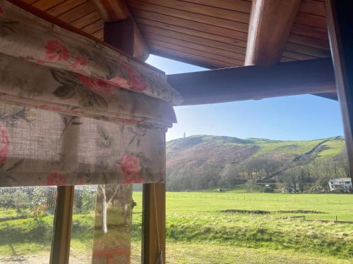 a window with a view of a field and mountains at Log home village in Ulverston