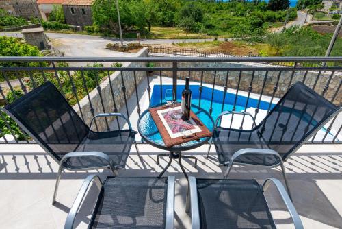 eine Terrasse mit 3 Stühlen und einem Tisch mit einer Flasche Wein in der Unterkunft Apartments Villa Kabalero in Gruda