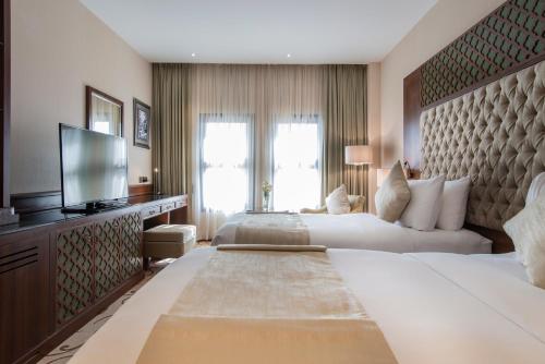 a hotel room with two beds and a flat screen tv at Vittori Palace Hotel and Residences in Riyadh