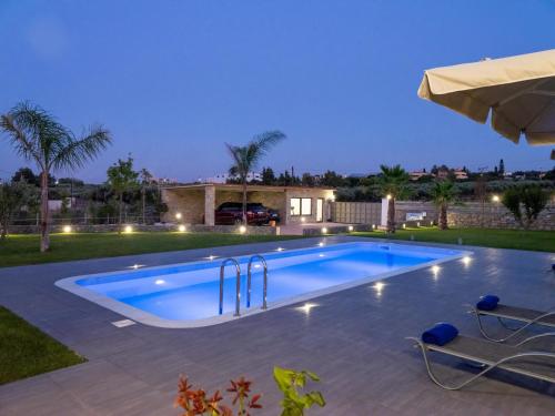 una piscina en un patio trasero por la noche en Luxurious Villa David, en Áno Kalésia